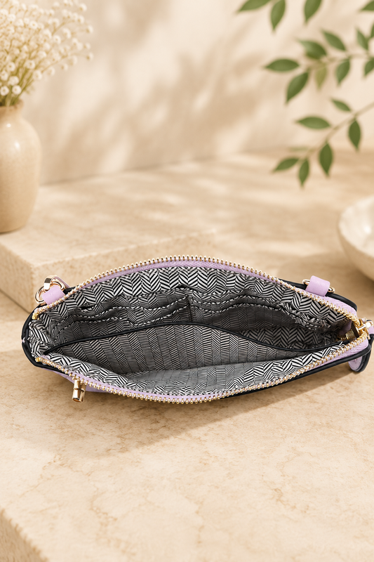 An open zippered pouch with a black and white geometric patterned interior lining and light purple zipper pulls, displayed on a beige stone surface with soft-focus decorative background elements.
