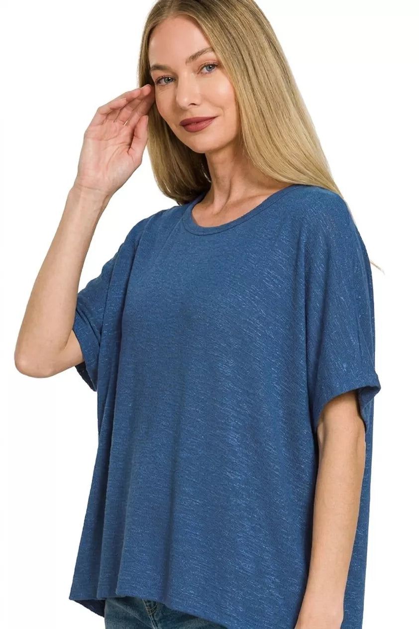 Woman wearing a light navy oversized slub hacci knit top by Zenana featuring a relaxed fit, short sleeves, crew neckline, and draped hem. Side View 2