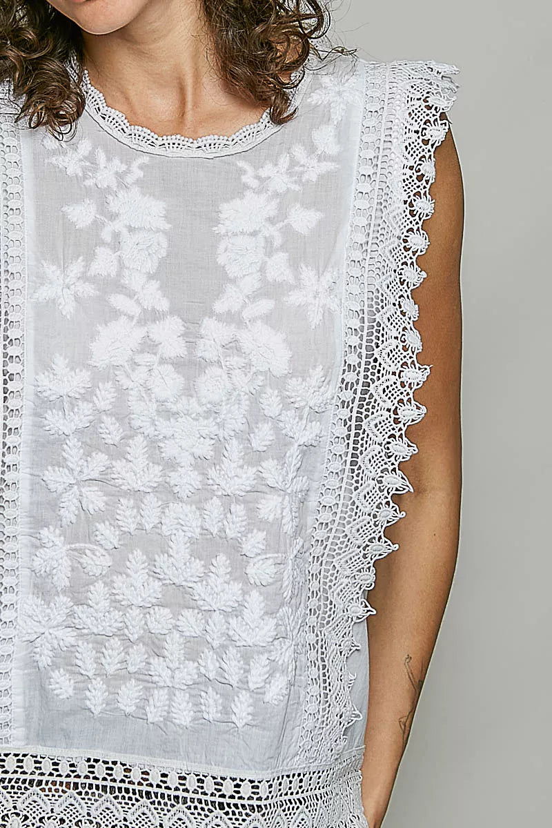 Woman wearing an off white sleeveless cotton top featuring botanical embroidery and scalloped lace trim by POL. Close View
