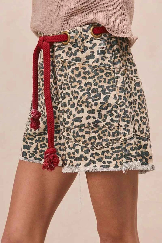 Woman wearing leopard print cotton shorts with a braided tassel waist belt, raw hem, and oversized front patch pockets by BiBi. Side View