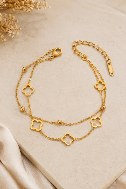 18K gold double chain bracelet featuring polished open clover charms and delicate gold bead accents on a tarnish-free stainless steel chain.
