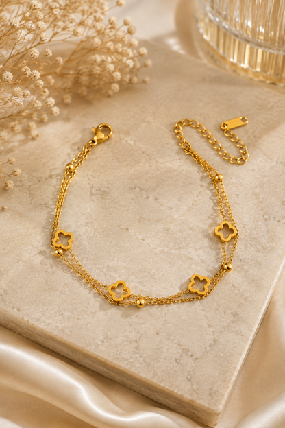18K gold double chain bracelet featuring polished open clover charms and delicate gold bead accents on a tarnish-free stainless steel chain. Flat lay