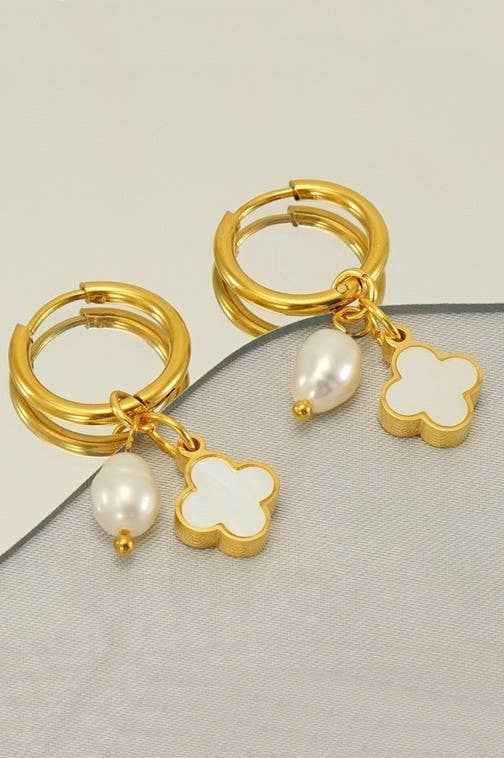 18K gold stainless steel huggie hoop earrings featuring a white clover charm and pearl drop displayed on a neutral boutique background.