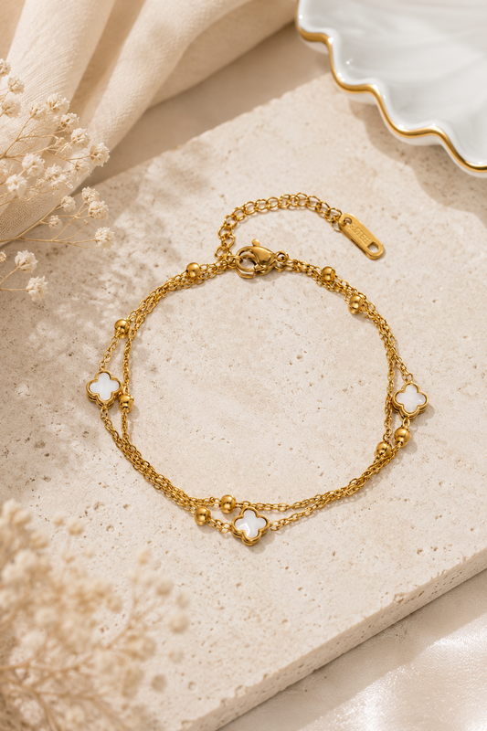 18K gold stainless steel layered chain bracelet featuring white clover charms and polished gold bead accents.
