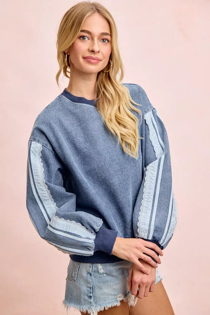 Woman wearing a washed denim lace contrast sweatshirt with long sleeves and relaxed fit by BiBi.