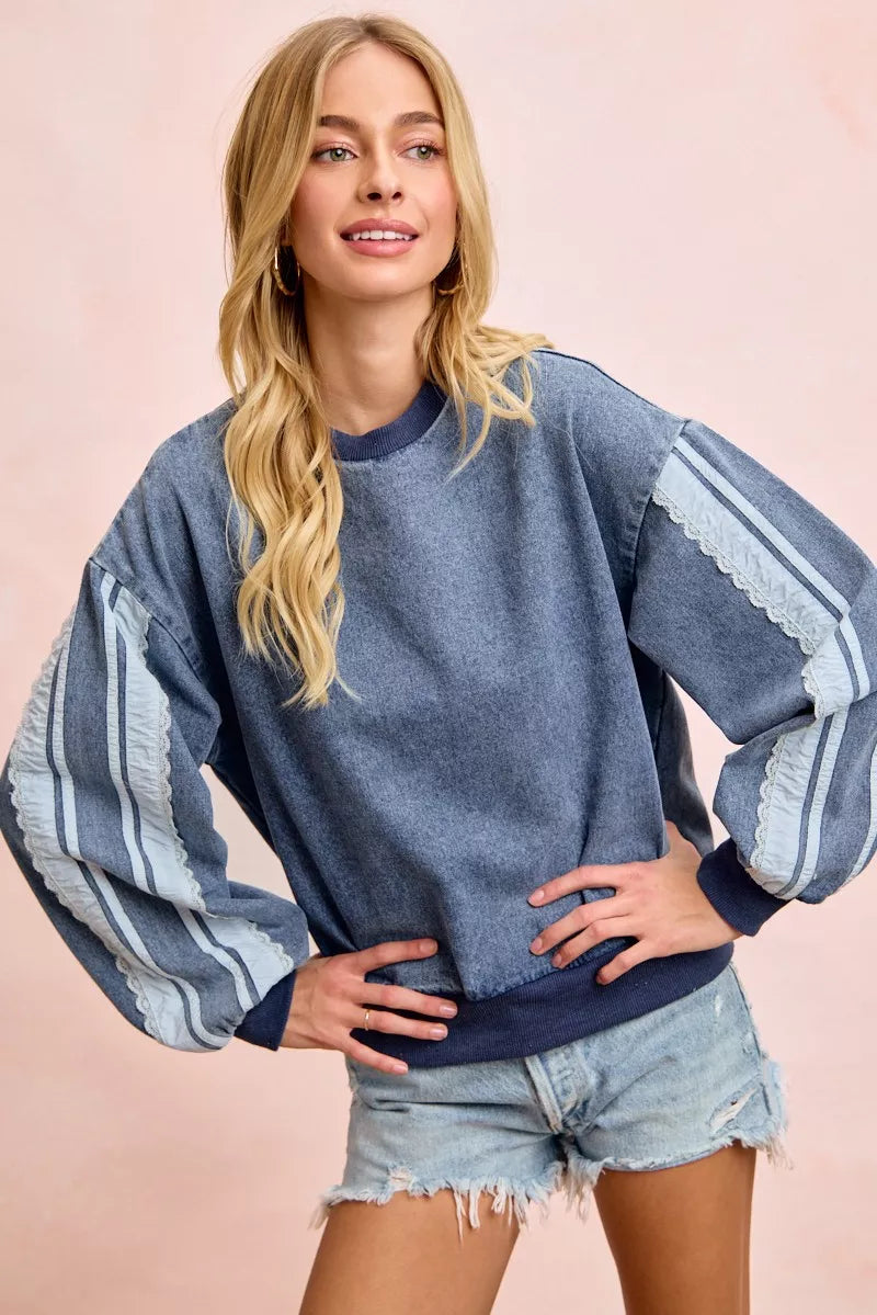 Woman wearing a washed denim lace contrast sweatshirt with long sleeves and relaxed fit by BiBi.