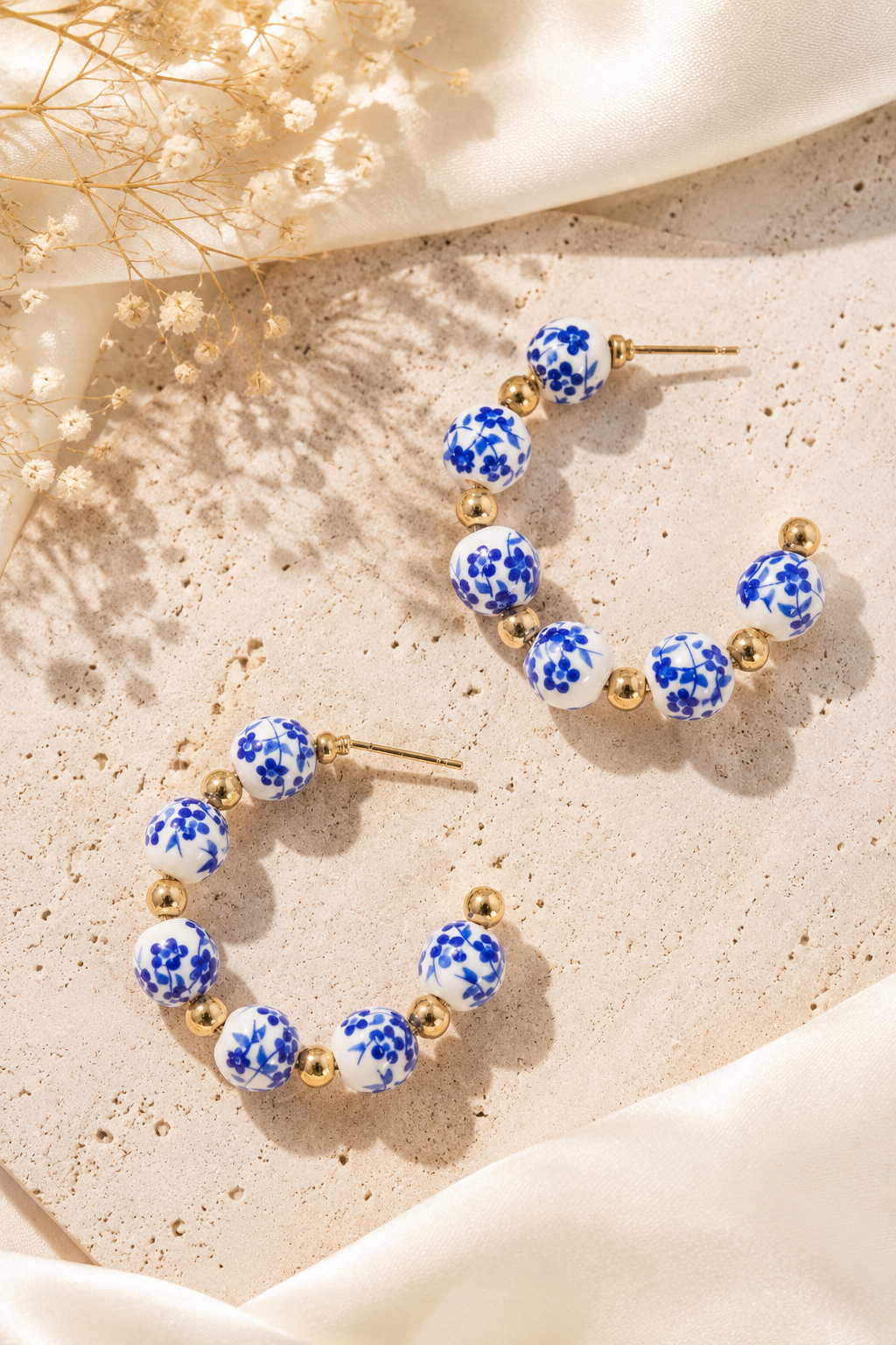 Blue floral porcelain hoop earrings with 18K gold stainless steel accents featuring elegant ceramic beads and a timeless hoop design.