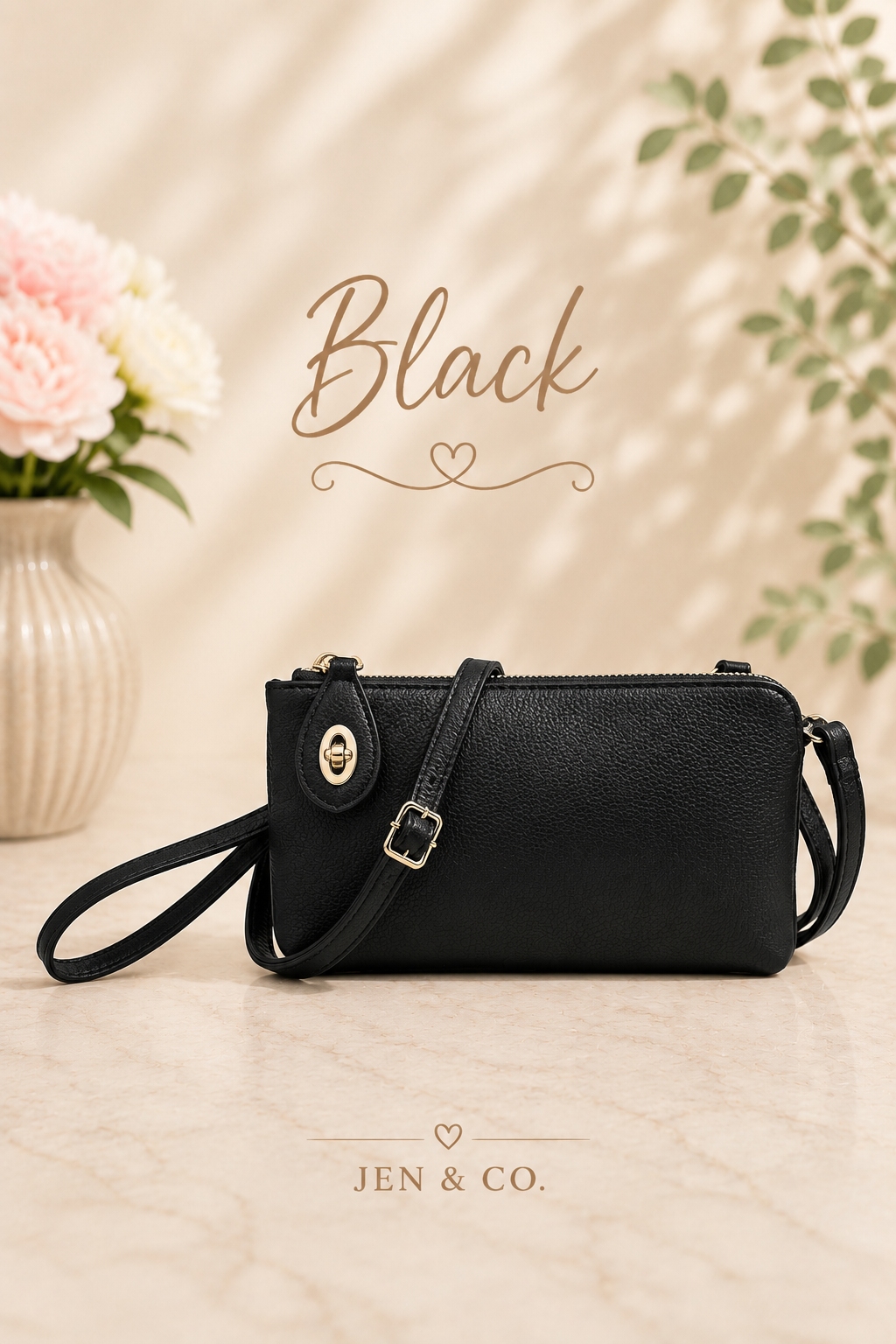A black pebbled leather crossbody clutch bag with a wristlet strap and gold-tone hardware, displayed on a marble surface with decorative flowers and text overlays reading 'Black' and 'JEN & CO.'.