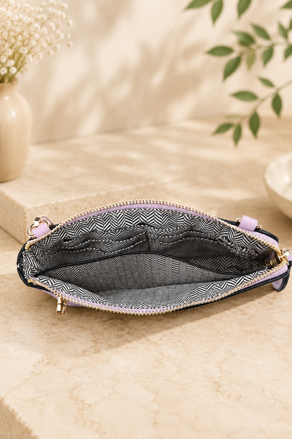 An open zippered pouch with a black and white geometric patterned interior lining and light purple zipper pulls, displayed on a beige stone surface with soft-focus decorative background elements.