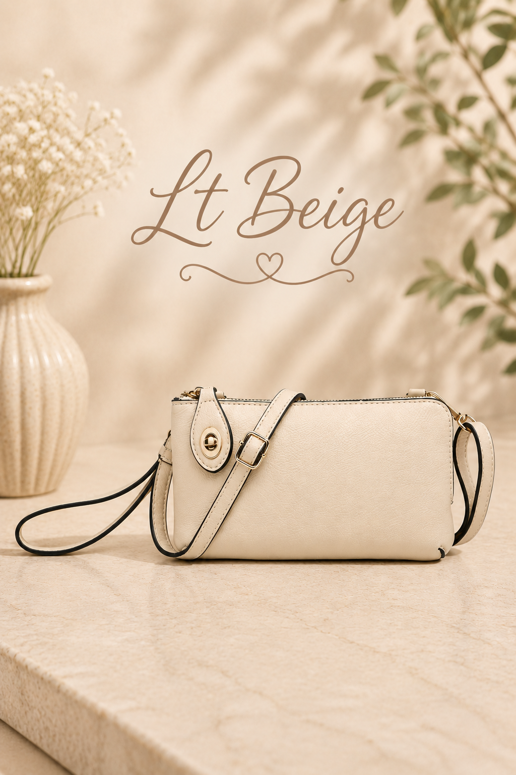 A light beige faux-leather crossbody handbag with a black wristlet strap, resting on a marble surface with a beige vase of baby's breath and green leaves in the background. The text 'Lt Beige' is written in the upper center.