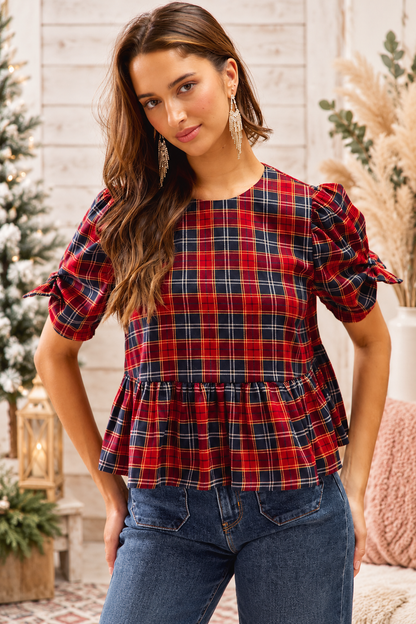 So Me Christmas red and navy plaid peplum top with puff sleeves and ribbon bow details on a model