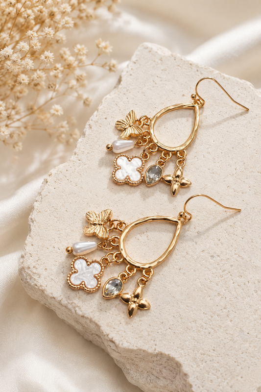 Gold multi-charm teardrop earrings with butterfly, shell clover, pearl, crystal, and floral charms. Flat Lay 2