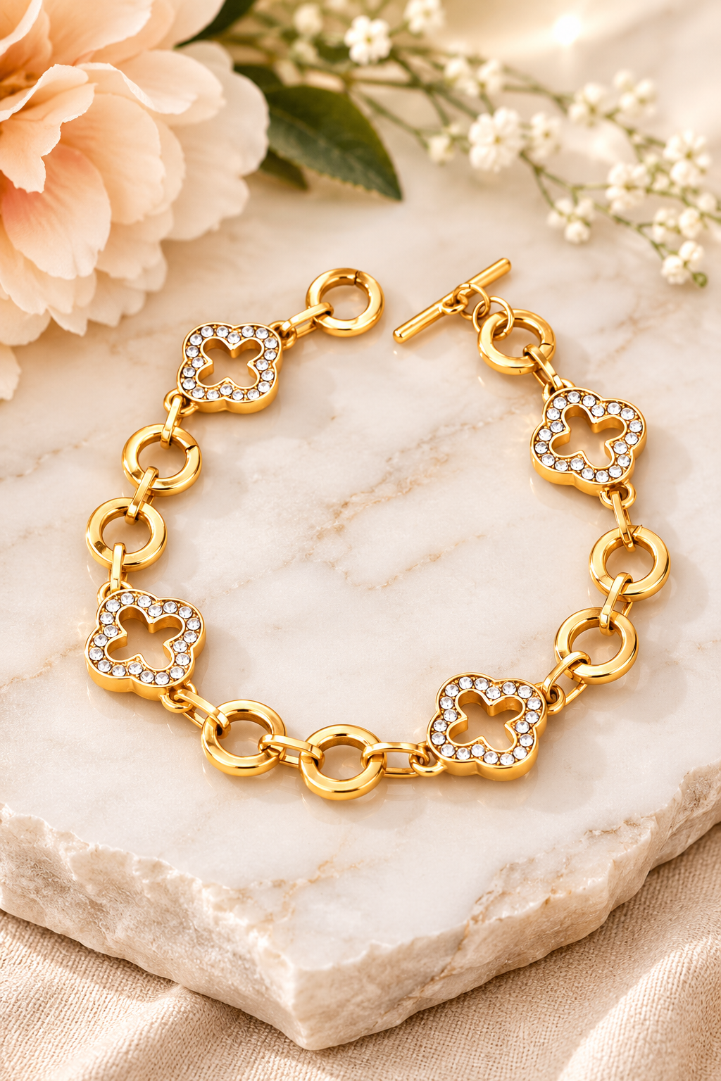 Gold pavé crystal clover link bracelet with toggle clasp featuring sparkling rhinestone quatrefoil charms and polished gold links.