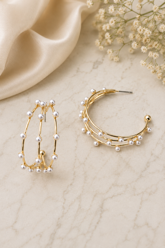 Gold triple row pearl hoop earrings featuring delicate faux pearls on lightweight open hoop posts.