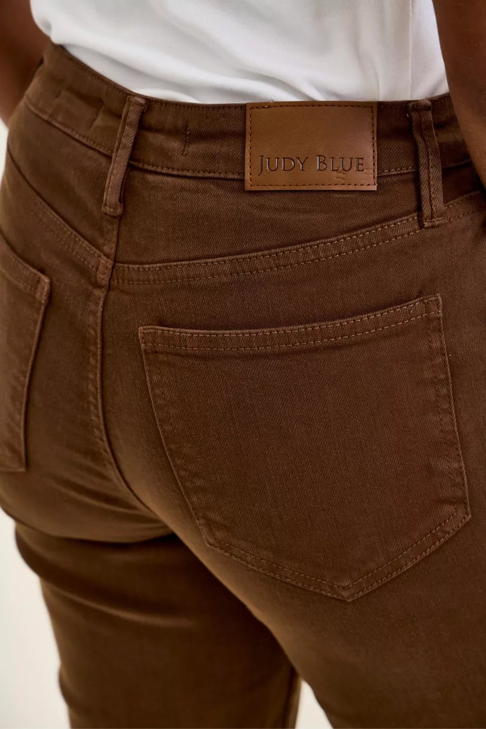 Model wearing Judy Blue Aurora Weekender high waist mahogany jeans with knee dart detailing and ankle-length silhouette. Tag View