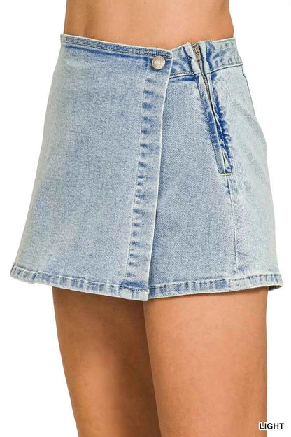 Side view of a Zenana light wash denim wrap skort featuring a button closure, asymmetrical overlap design, mini length, and built-in shorts.