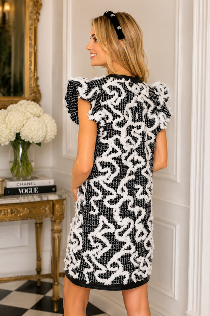 VOY black and white textured above knee dress with ruffle sleeves ribbon bow and gold buttons back view