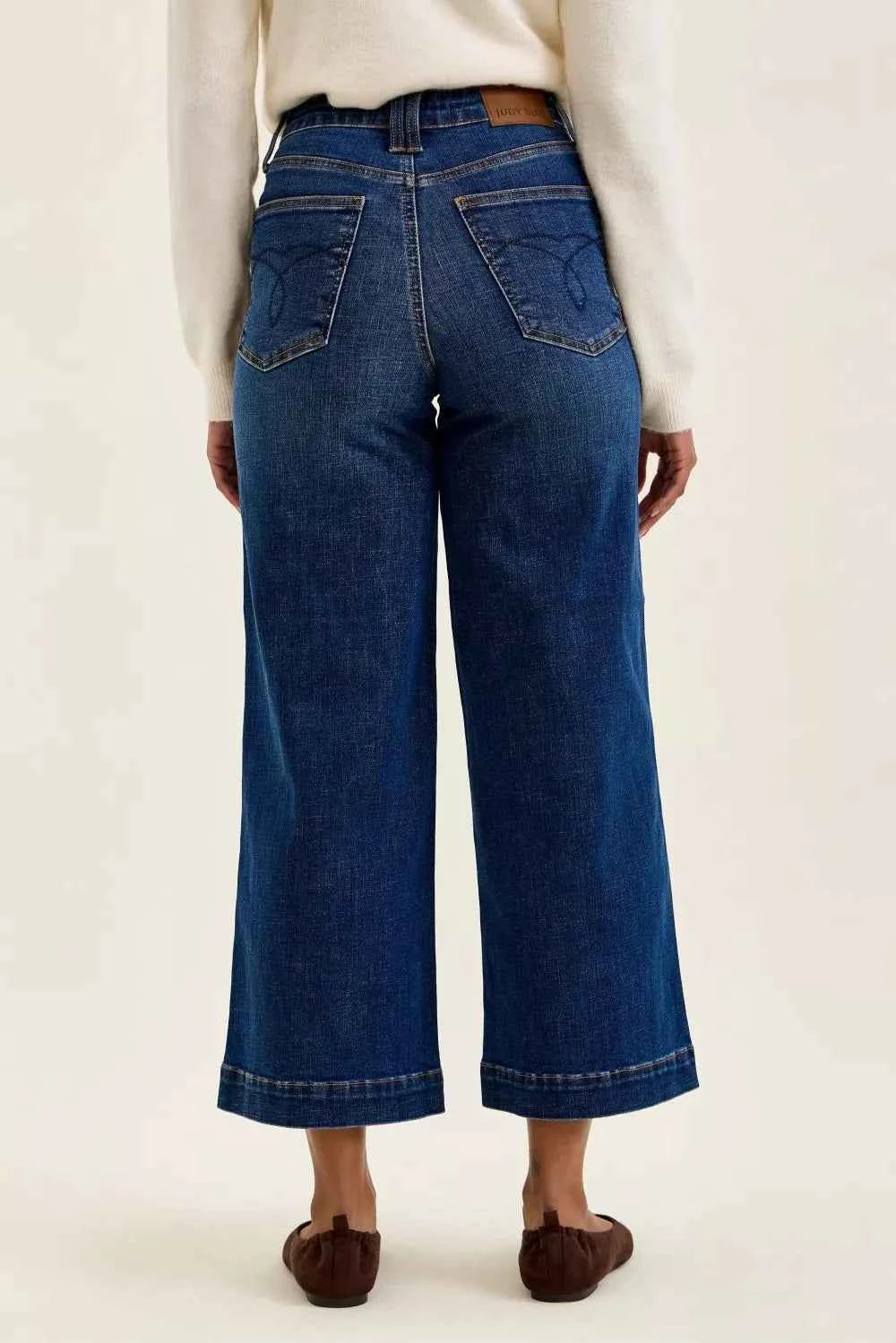 Woman wearing Judy Blue Claudia high waist tummy control ankle wide leg jeans in a dark indigo wash with a flattering modern silhouette. Back View