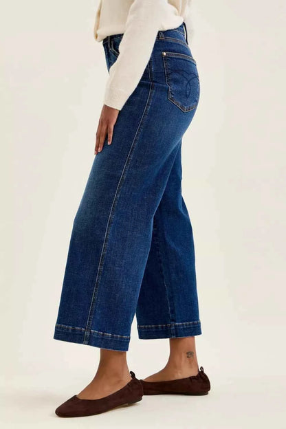 Woman wearing Judy Blue Claudia high waist tummy control ankle wide leg jeans in a dark indigo wash with a flattering modern silhouette. Side View