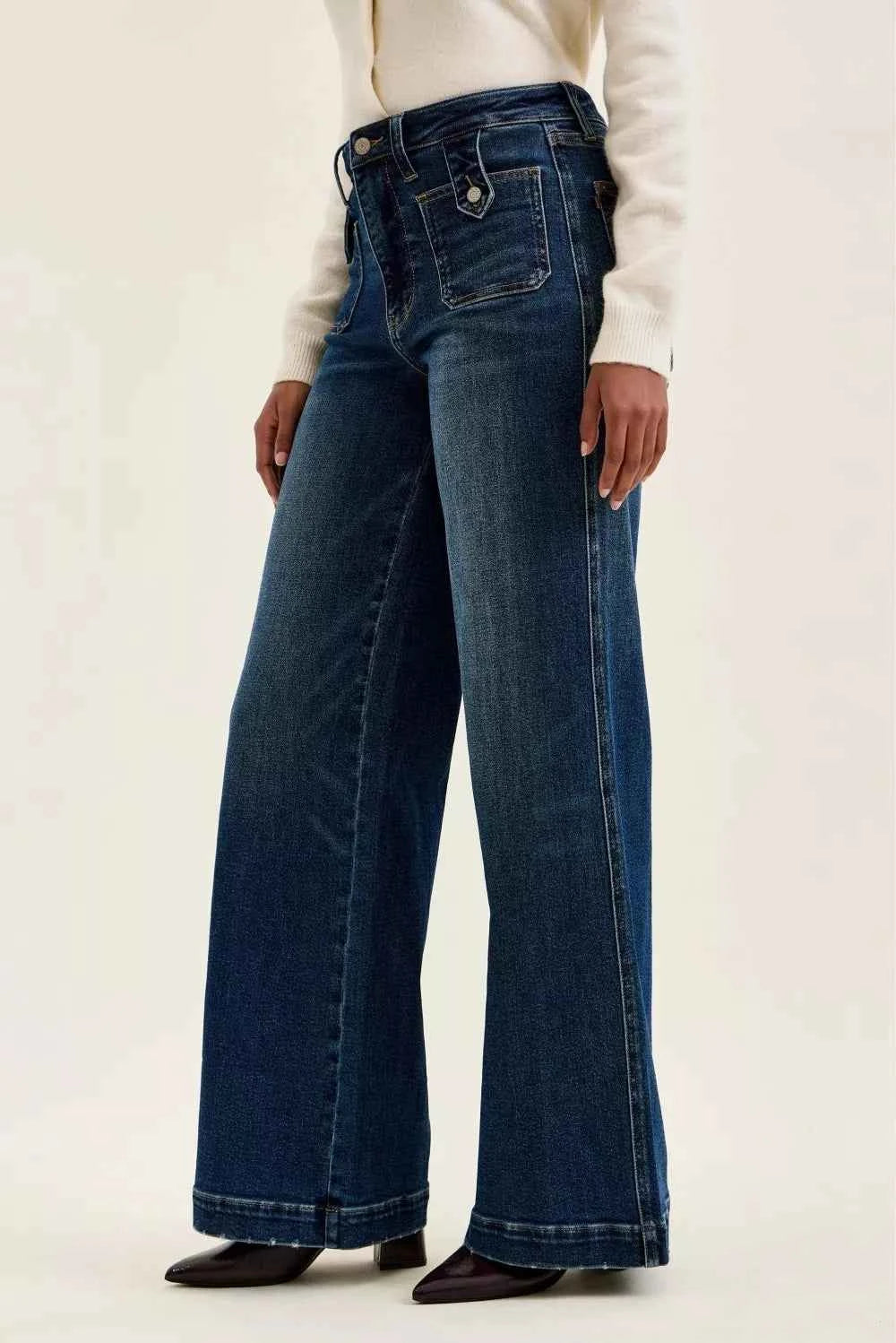 Woman wearing Judy Blue Lux high waist retro wide leg jeans in dark indigo wash with front patch pockets and a vintage-inspired silhouette. Side view 2