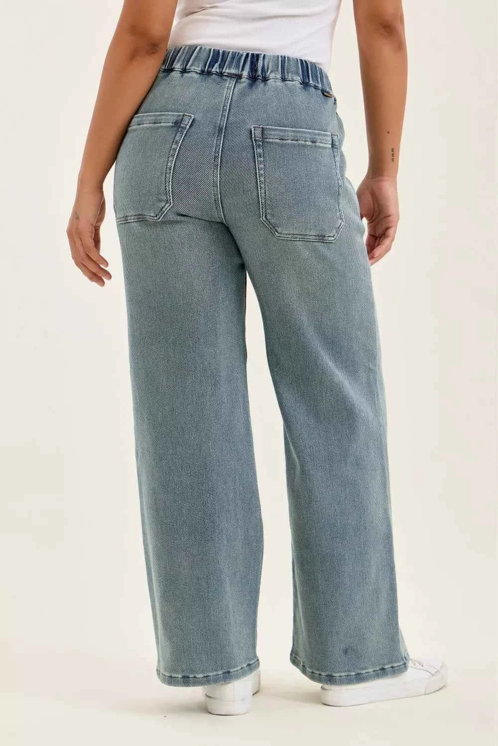 Woman wearing Judy Blue high waist drawstring baggy jeans in a medium aged stone blue wash with a relaxed wide-leg fit.
 Back View