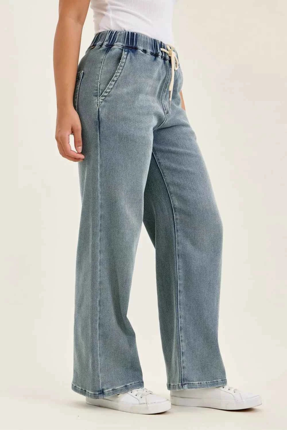 Woman wearing Judy Blue high waist drawstring baggy jeans in a medium aged stone blue wash with a relaxed wide-leg fit.
 Side View