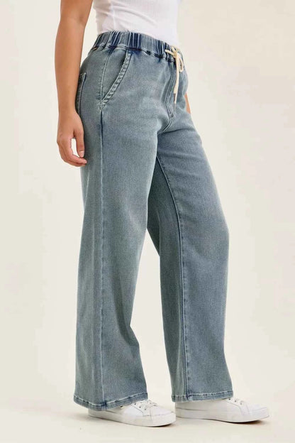 Woman wearing Judy Blue high waist drawstring baggy jeans in a medium aged stone blue wash with a relaxed wide-leg fit.
 Side View