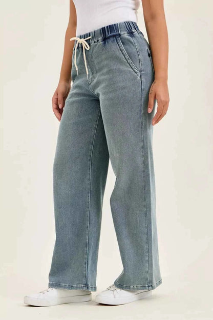 Woman wearing Judy Blue high waist drawstring baggy jeans in a medium aged stone blue wash with a relaxed wide-leg fit.
 Side View 2
