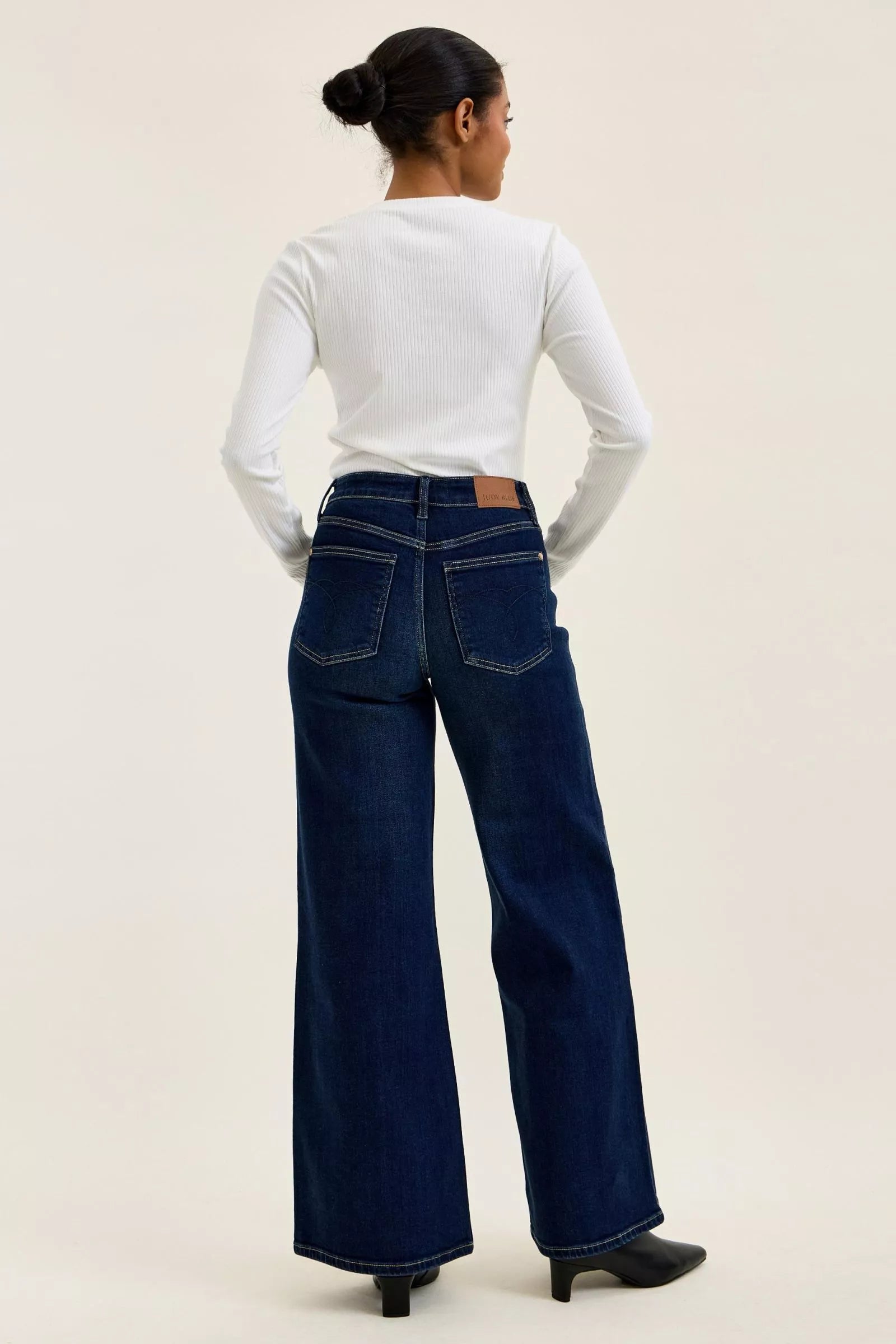 Woman wearing Judy Blue high waist wide leg dark wash jeans with a relaxed silhouette and premium stretch denim.
 full back view