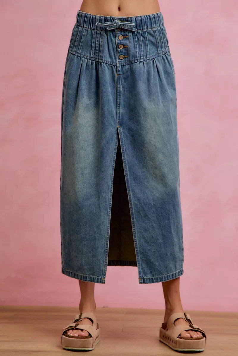 Woman wearing SO ME high waist button front denim maxi skirt with drawstring waistband, pleated waist detail, distressed wash, and front slit. Front View 2