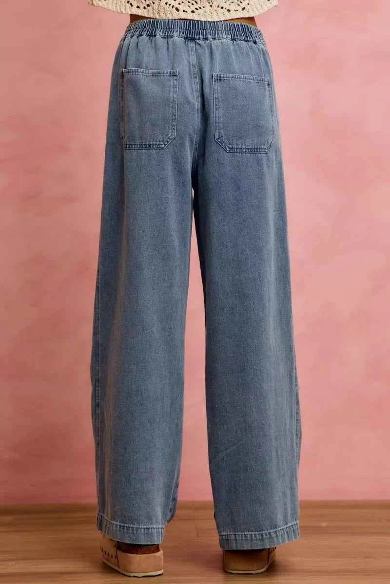 Woman wearing SO ME mid rise wide leg jeans with ruffled front detailing, elastic waistband, and lightweight denim construction.
 Back View