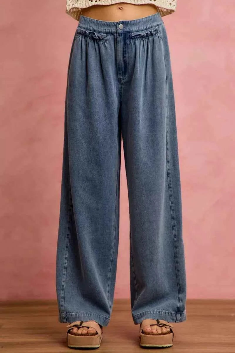 Woman wearing SO ME mid rise wide leg jeans with ruffled front detailing, elastic waistband, and lightweight denim construction.
 Front View