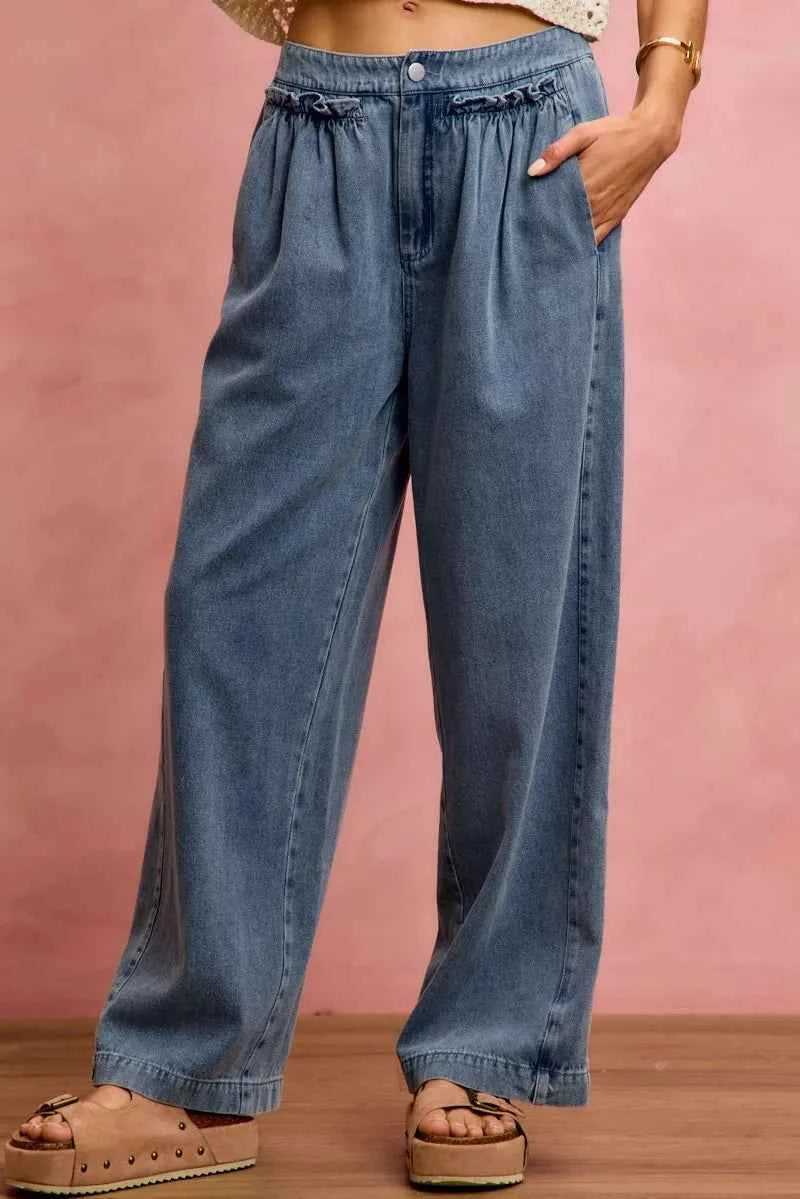 Woman wearing SO ME mid rise wide leg jeans with ruffled front detailing, elastic waistband, and lightweight denim construction.
 Front View 2