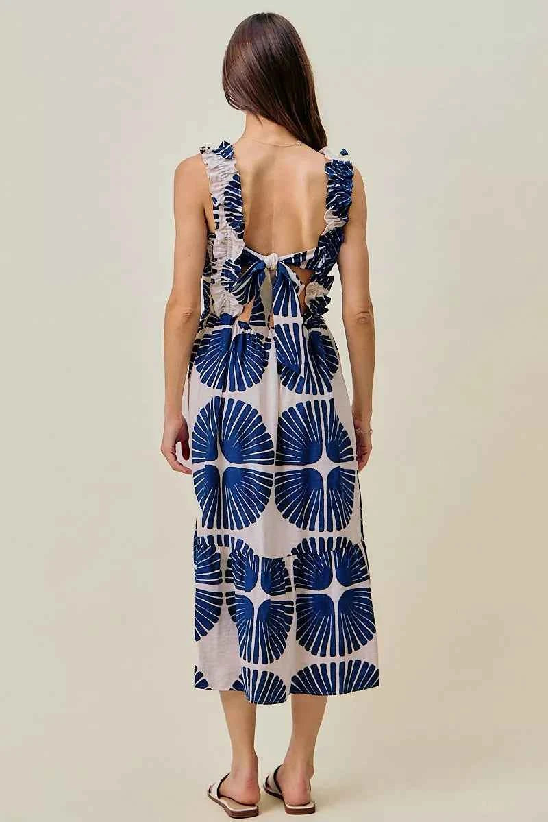 Woman wearing SO ME navy abstract print smocked bodice tiered midi dress featuring ruffle straps, a flowy tiered skirt, and a flattering feminine silhouette. Back View