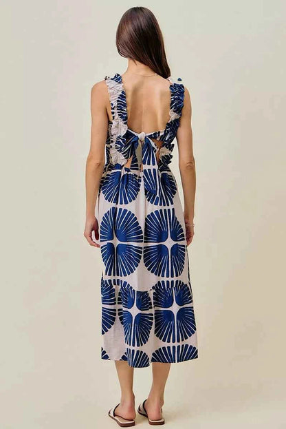 Woman wearing SO ME navy abstract print smocked bodice tiered midi dress featuring ruffle straps, a flowy tiered skirt, and a flattering feminine silhouette. Back View
