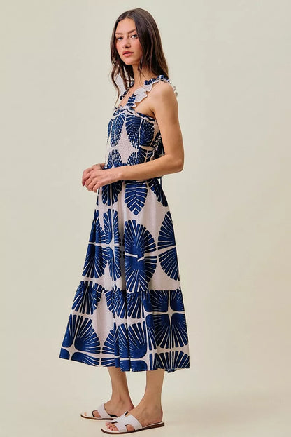 Woman wearing SO ME navy abstract print smocked bodice tiered midi dress featuring ruffle straps, a flowy tiered skirt, and a flattering feminine silhouette. Side view