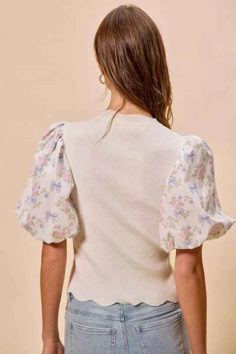 Woman wearing SO ME white floral contrast sleeve scallop sweater top featuring puff sleeves, lightweight knit fabric, feminine floral print, and scalloped trim detail. Back View