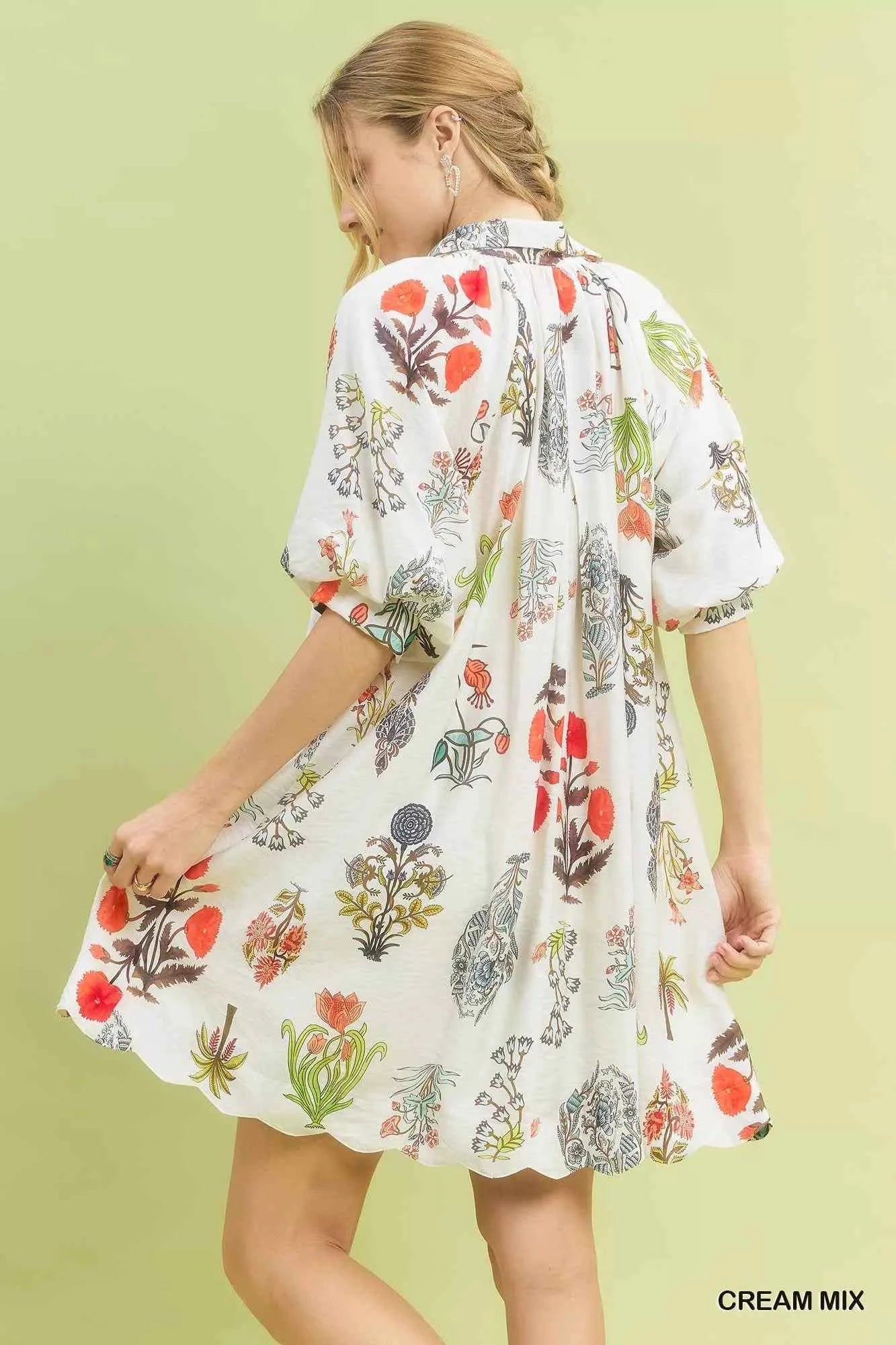 Woman wearing Umgee Cream Botanical Print Mini Dress with pockets, relaxed fit, vintage floral illustrations, and lightweight fabric. Back View
