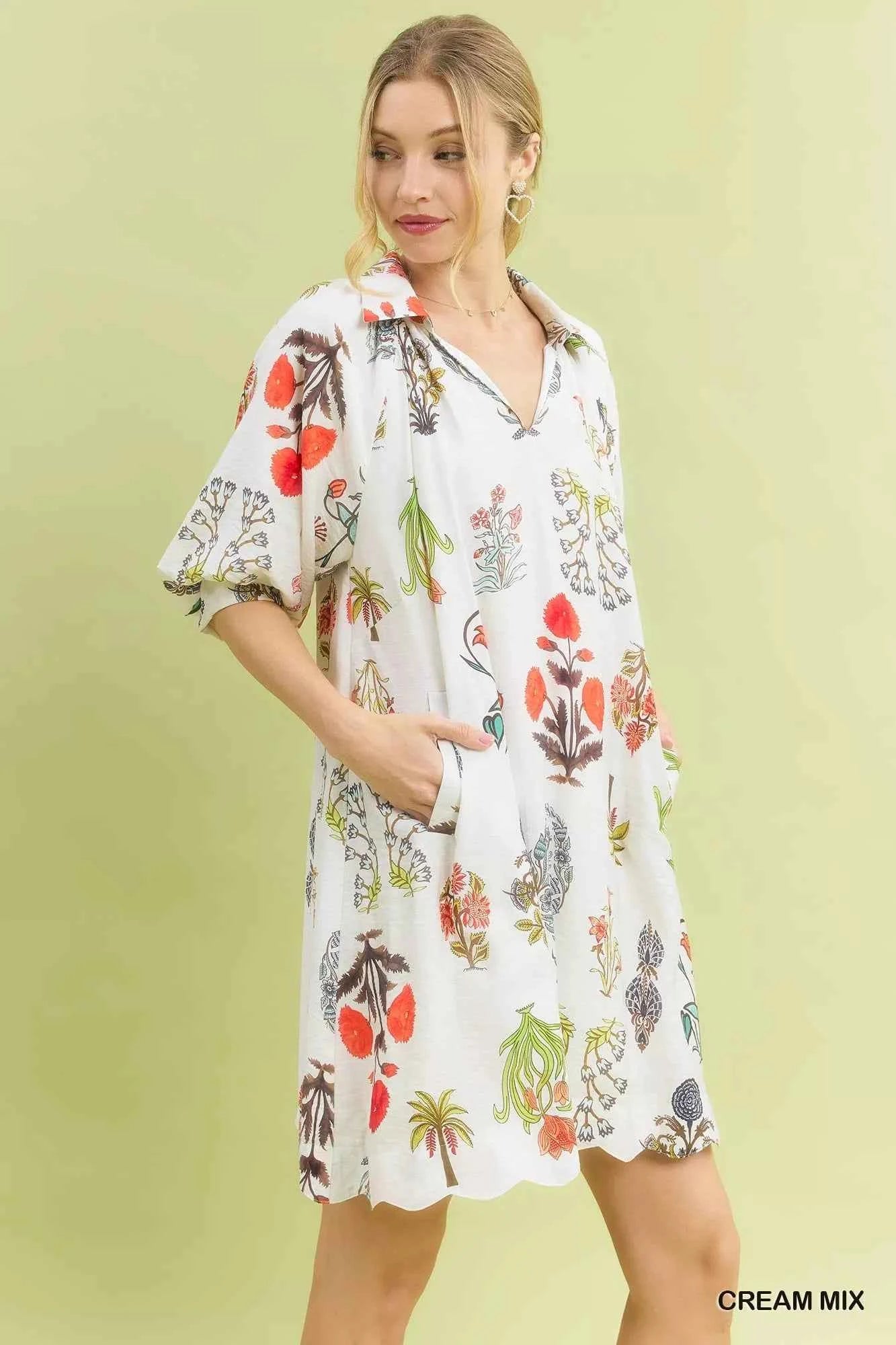 Woman wearing Umgee Cream Botanical Print Mini Dress with pockets, relaxed fit, vintage floral illustrations, and lightweight fabric. Side View