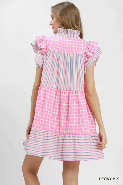 Woman wearing Umgee Peony Pink Patchwork Flutter Sleeve Tiered Dress with ruffle sleeves, striped accents, and a relaxed boho silhouette. Back View