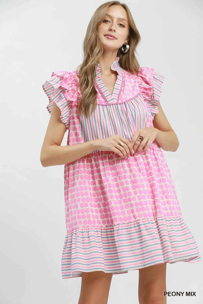 Woman wearing Umgee Peony Pink Patchwork Flutter Sleeve Tiered Dress with ruffle sleeves, striped accents, and a relaxed boho silhouette. Front view