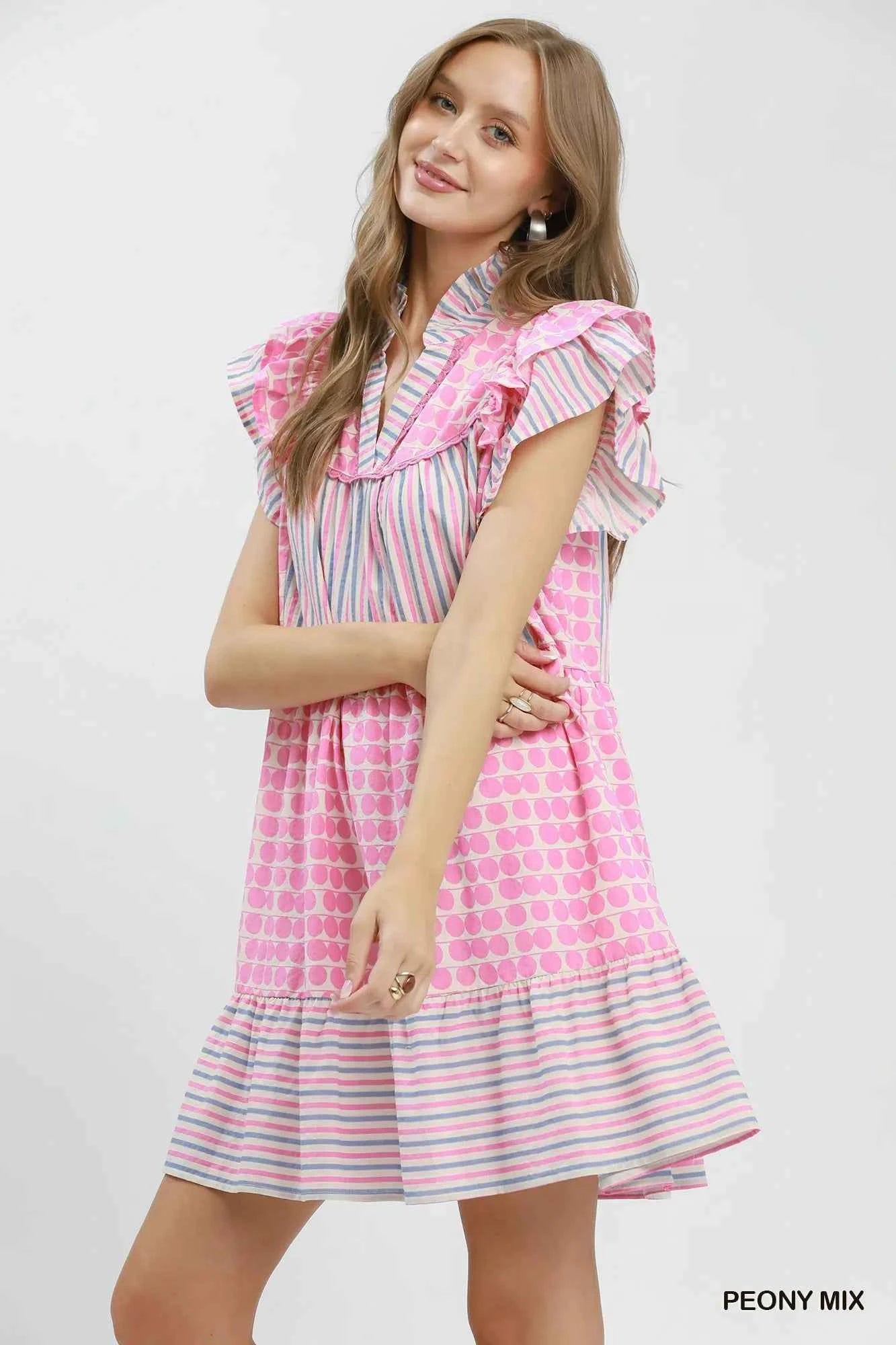 Woman wearing Umgee Peony Pink Patchwork Flutter Sleeve Tiered Dress with ruffle sleeves, striped accents, and a relaxed boho silhouette. Side View