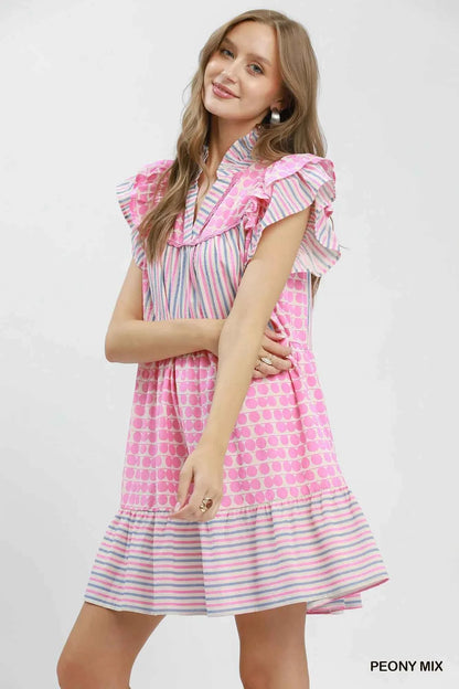 Woman wearing Umgee Peony Pink Patchwork Flutter Sleeve Tiered Dress with ruffle sleeves, striped accents, and a relaxed boho silhouette. Side View