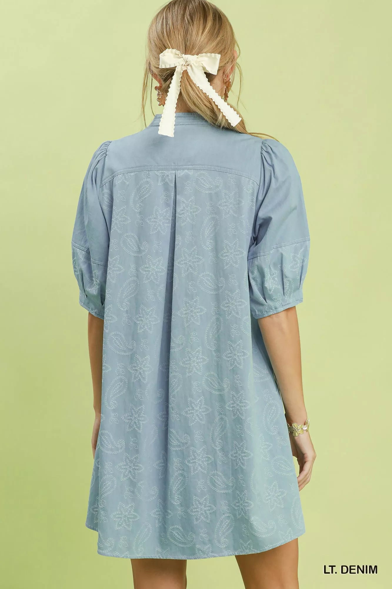 Woman wearing Umgee light denim paisley print dress with puff sleeves, split V-neck pintuck detail, relaxed fit, and side pockets. Back View