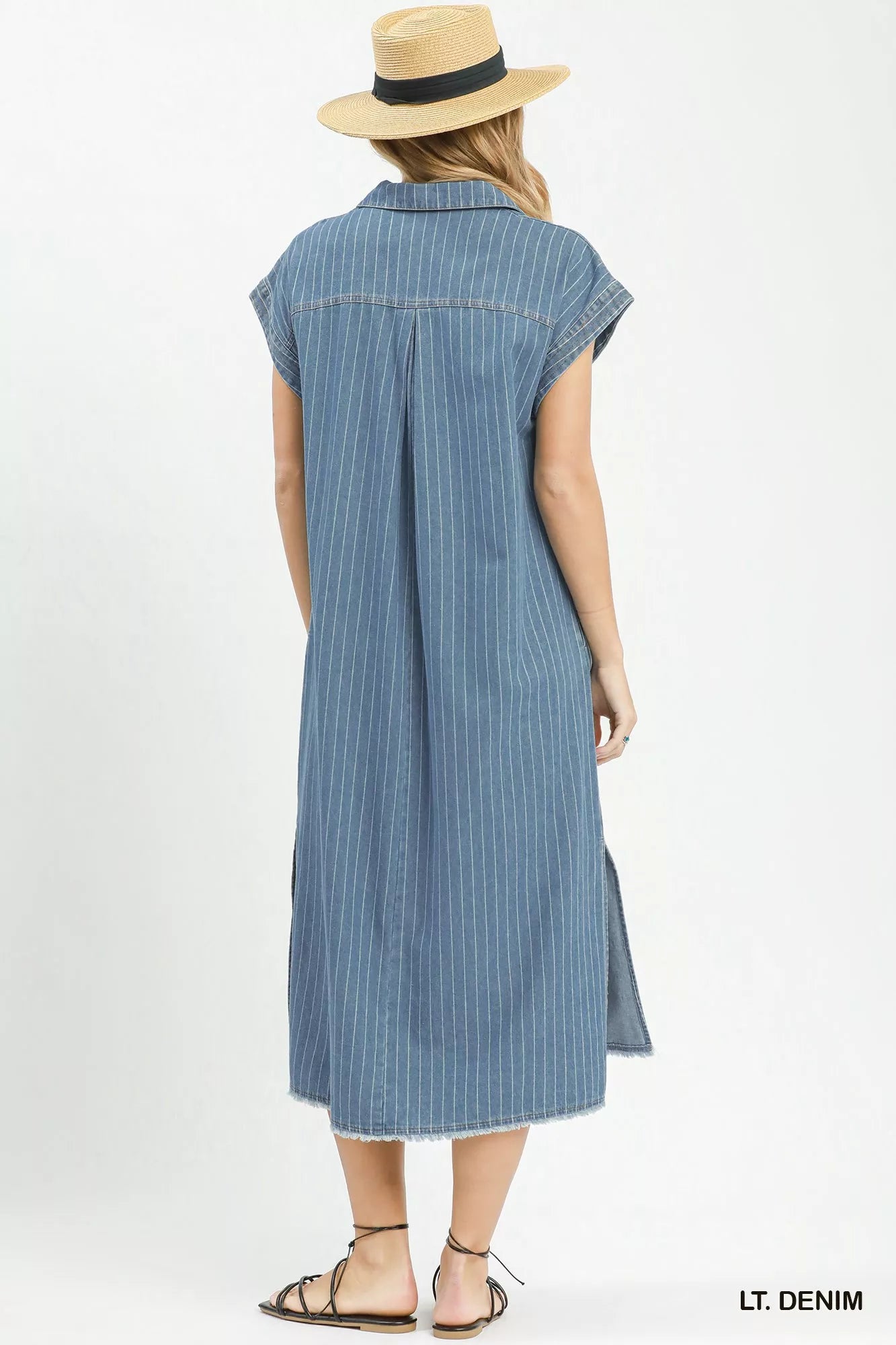 Woman wearing Umgee light denim pinstripe midi dress with collared split neckline, cap sleeves, side pockets, side slits, and raw hem detail. Back View