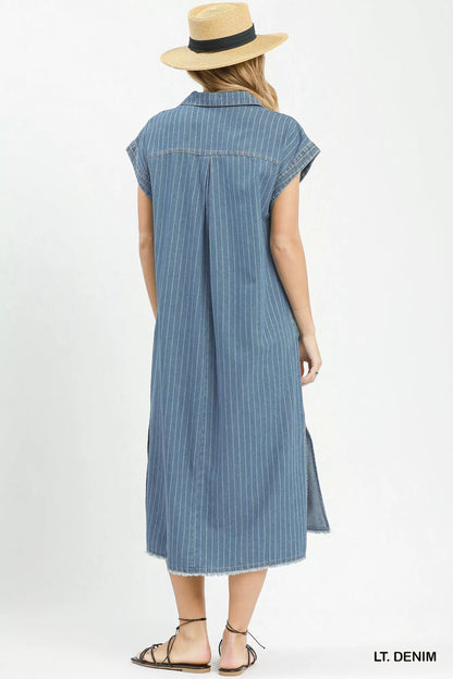 Woman wearing Umgee light denim pinstripe midi dress with collared split neckline, cap sleeves, side pockets, side slits, and raw hem detail. Back View