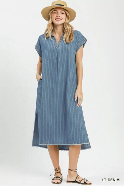 Woman wearing Umgee light denim pinstripe midi dress with collared split neckline, cap sleeves, side pockets, side slits, and raw hem detail. Front View