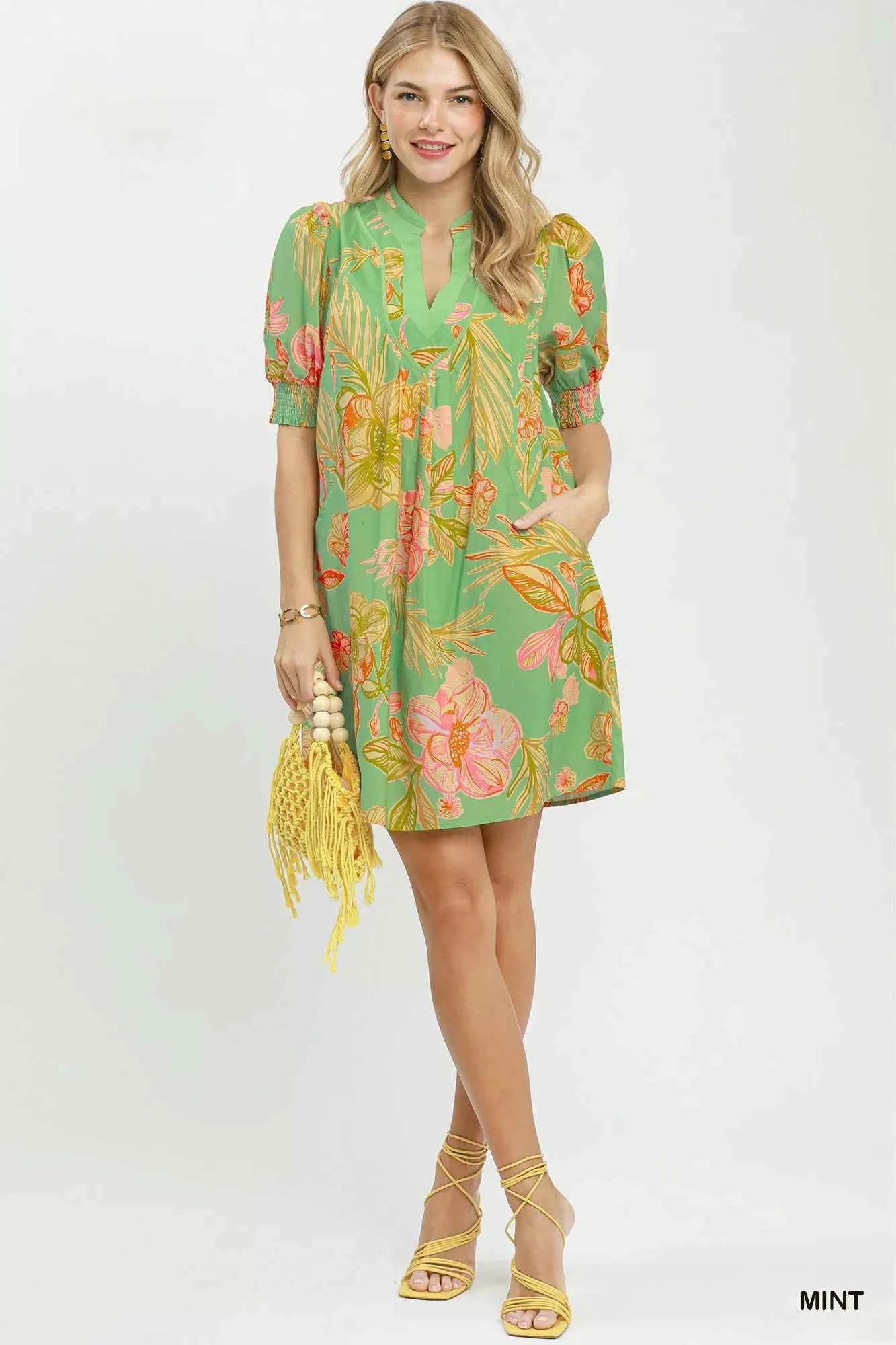 Woman wearing Umgee mint tropical floral dress with smocked sleeves, split V-neck, pockets, and flowy silhouette perfect for summer vacations and brunch. Full View