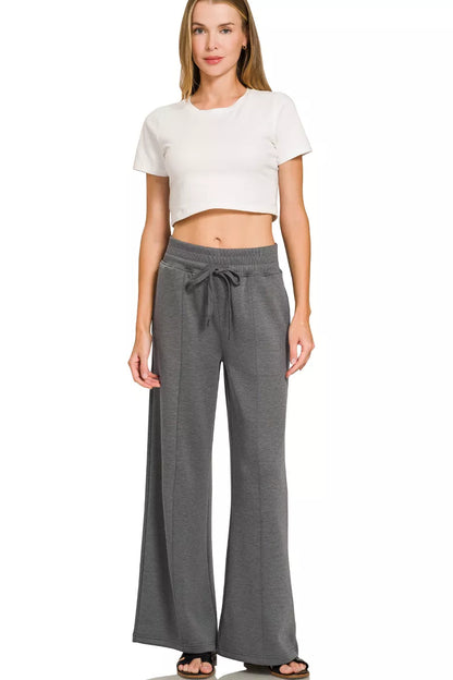 Woman wearing a Zenana charcoal scuba knit two-piece set featuring a collared short-sleeve pullover top and matching wide-leg pants with pockets.