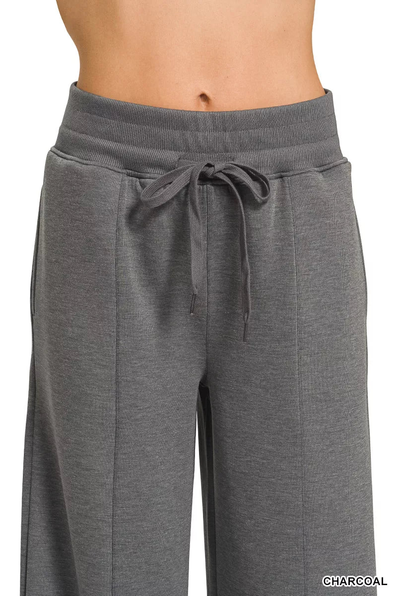 Woman wearing a Zenana charcoal scuba knit two-piece set featuring a collared short-sleeve pullover top and matching wide-leg pants with pockets.